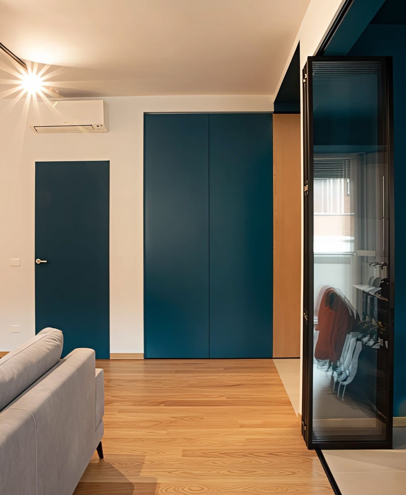 Casa Vito, Ferrara: zona giorno con porte a tutta altezza blu ottanio e parquet in rovere
